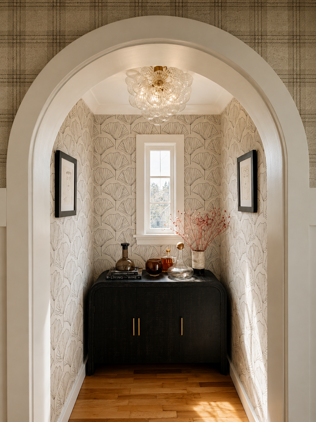 Beck Road bar alcove — arched opening with ginkgo leaf wallpaper, ebonized cabinet with brass pulls, floral glass chandelier, framed portraits