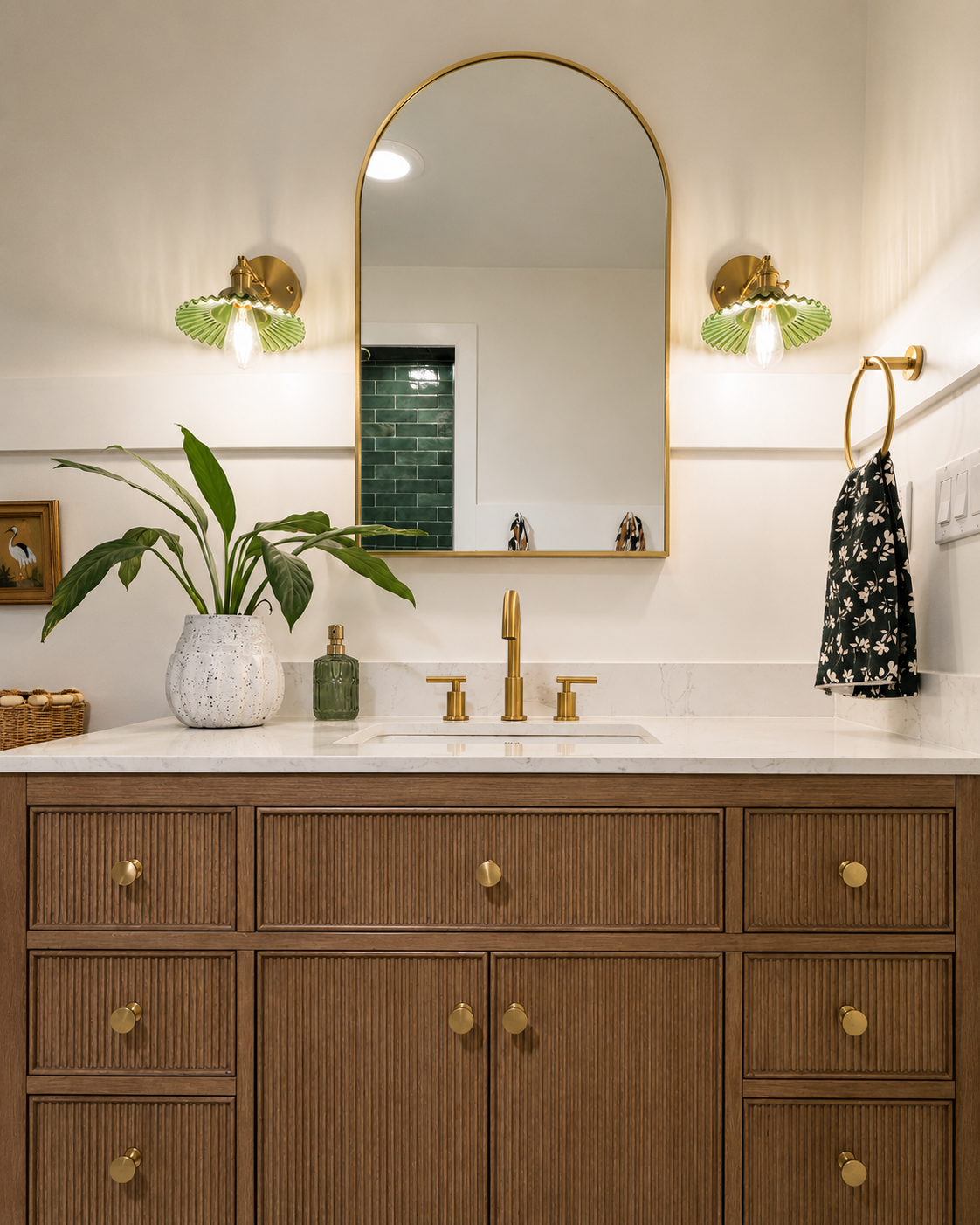 Beck Road guest bath — reeded oak vanity, brass hardware, arched gold mirror, green ribbed glass sconces, white quartz, geometric tile floor