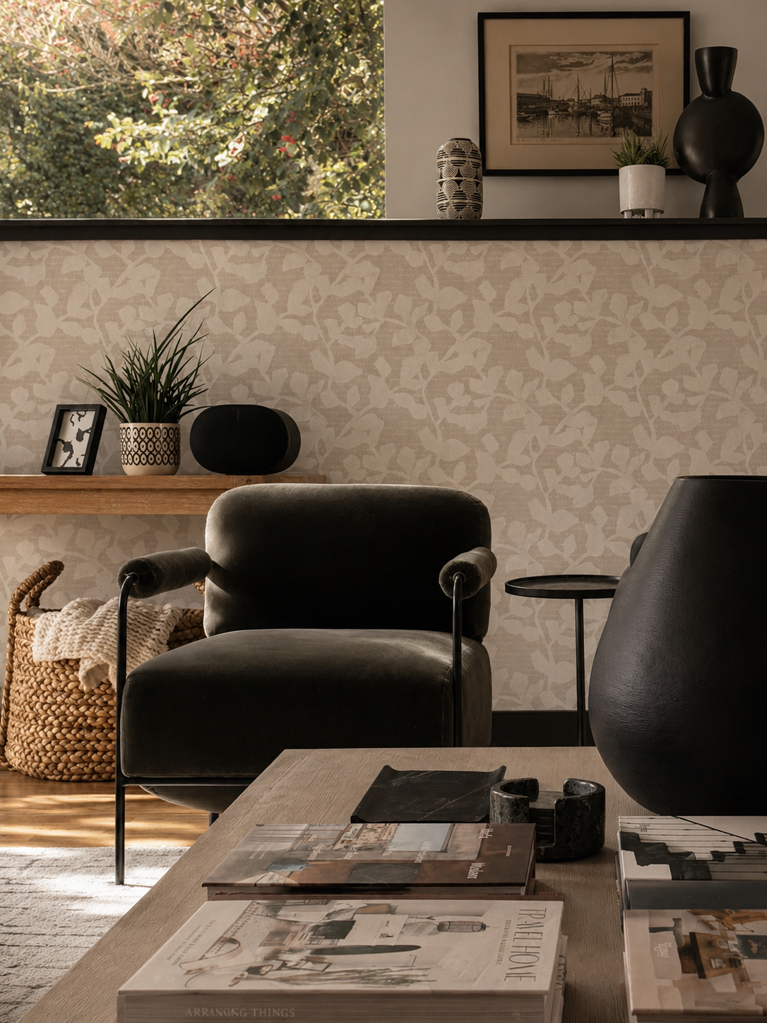Beck Road living room detail — olive charcoal velvet chair with metal arms, tonal botanical wallpaper, black display shelf, large window