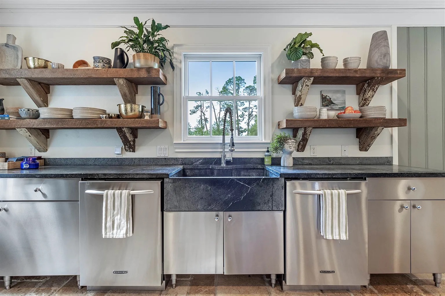Tyler Estate kitchen sink wall — soapstone farmhouse sink, reclaimed wood shelving on wood brackets, stainless steel cabinet boxes, commercial-grade appliances